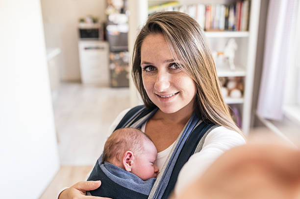 istock Beautiful young mother with son in sling taking selfie 614209292