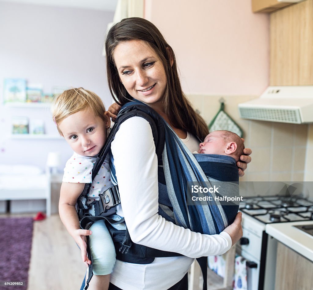 Mutter mit ihren Kindern in Schlingen und Babytrage - Lizenzfrei Familie mit zwei Kindern Stock-Foto