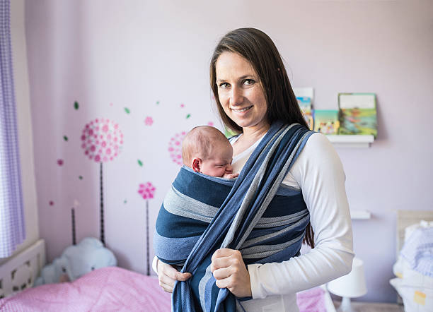 istock Beautiful young mother wrapping her son into sling 614211032