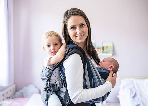 madre con i figli in fionda e baby carrier - famiglia con due figli foto e immagini stock