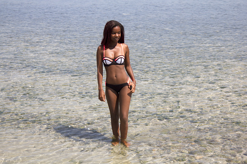 Image of a beautiful african woman in a bikini walking out the sea water on the beach