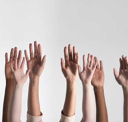 Shot of a diverse group of unidentifiable people holding their hands up against a white background