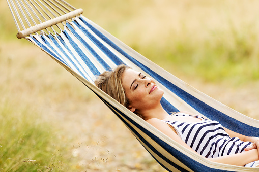 Young blonde woman resting on hammock.