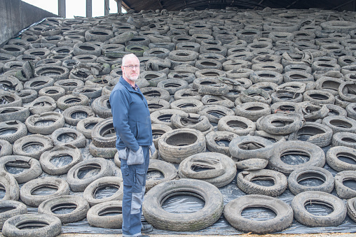 Proud farmer looking to camera, at his storage of silage for the winter, protected by plastic and tyres for preservation, Meath, Ireland. 
