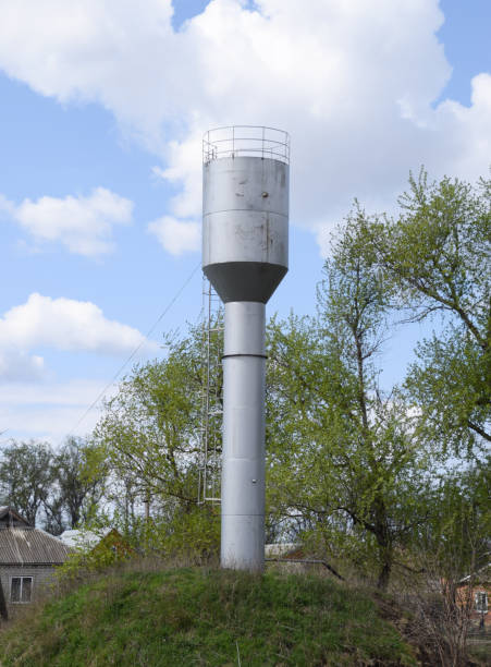 istock Silver Water Tower among green grass and trees 614213734