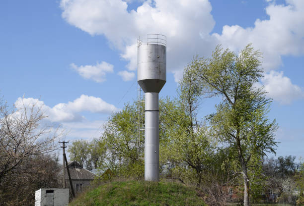 istock Silver Water Tower among green grass and trees 614214864