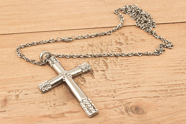 istock Silver christian cross with small diamonds on wooden board 614216596