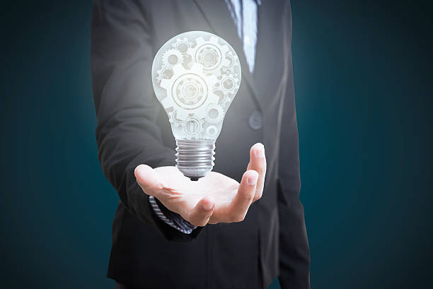 istock business hand holding electric light bulb with gear wheels. 614219878