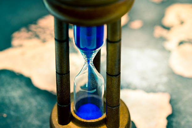 istock Hourglass against grunge world map 614220226