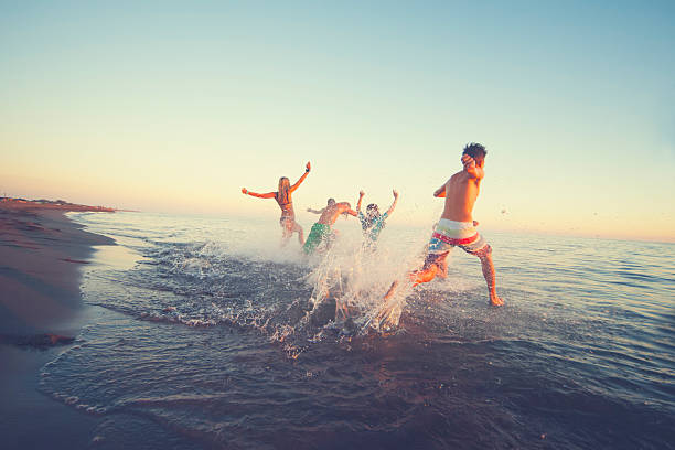 istock Friends running in to sea 614223366