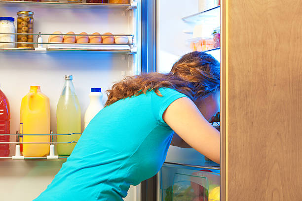 istock Dieting Hungry Woman Digging in Open Refrigerator for Food 614223644