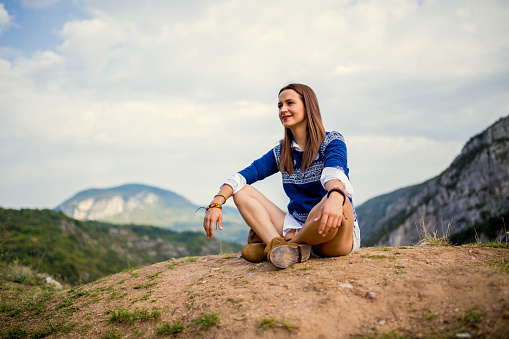 Girl sitting on a mountain top.