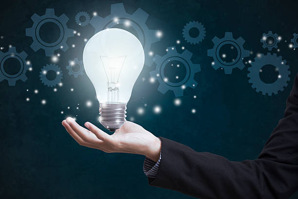 istock business hand holding electric light bulb with gear wheels. 614224696