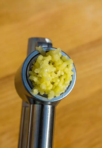 Photo of fresh crushed garlic in a press
