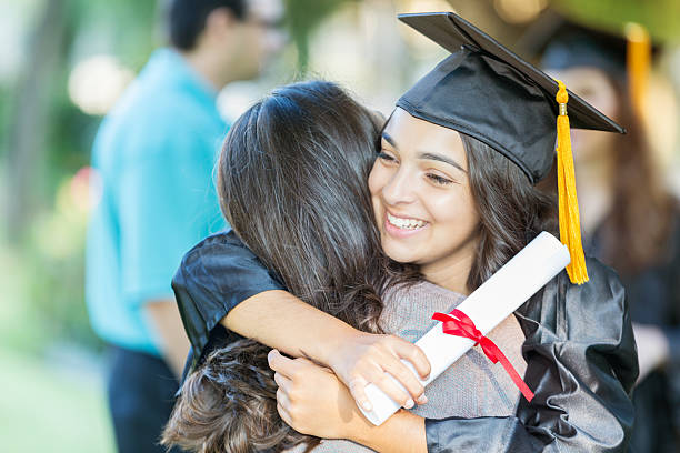 istock Smiling college grad embraces friend 614225316