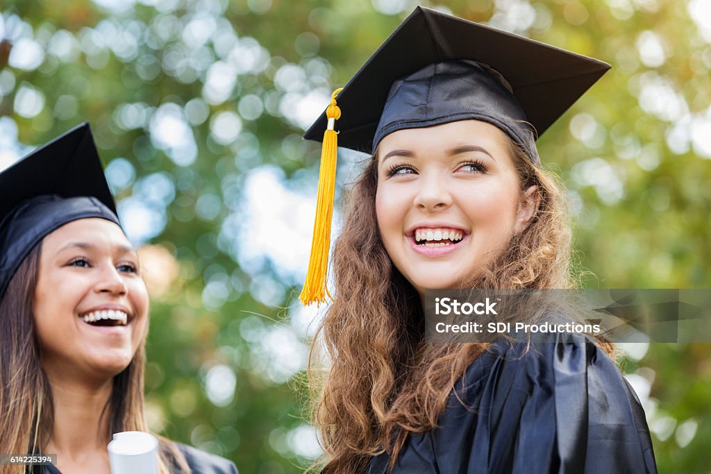 Cheerful Caucasian college graduate outdoors Beautiful Caucasian college graduate smiles confidently outdoors after graduation ceremony. Graduation Stock Photo