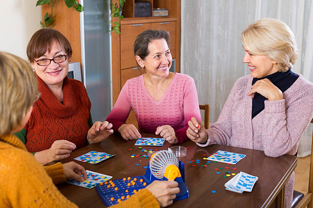 female friends sitting with lotto Positive senior female friends sitting at desk with lotto indoor dibs stock pictures, royalty-free photos & images