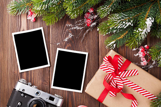 Blank photos with christmas gift, pine tree and camera Blank photo frames with christmas gift box, pine tree and camera on wooden table. Top view two objects photos stock pictures, royalty-free photos & images