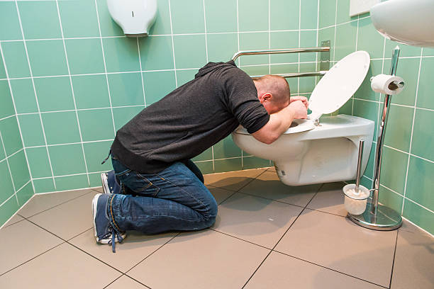 man vomiting in the toilet stock photo