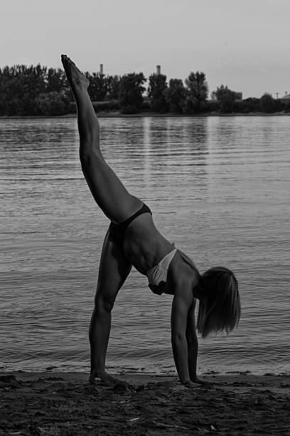 Beautiful young girl exercising in swimsuit exercise on the beach