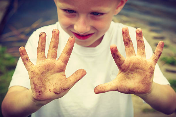 istock Child playing outdoor showing dirty muddy hands. 614237620