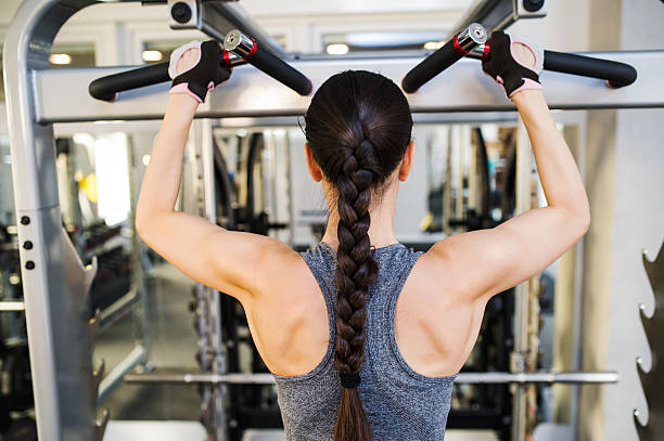 istock Woman in gym flexing back muscles on cable machine 614238314