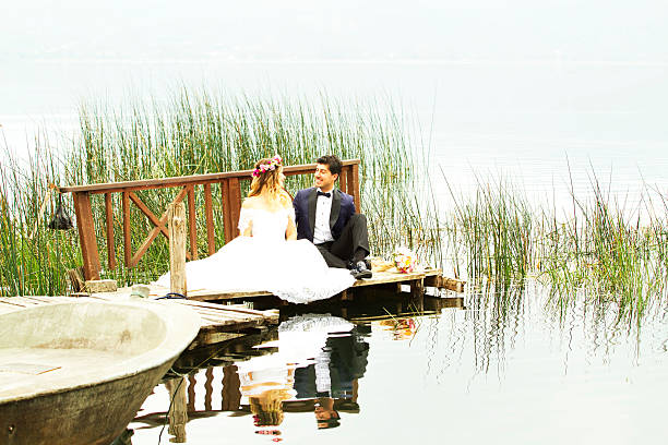 istock Bride and groom posing at a dock on the lake 614242236