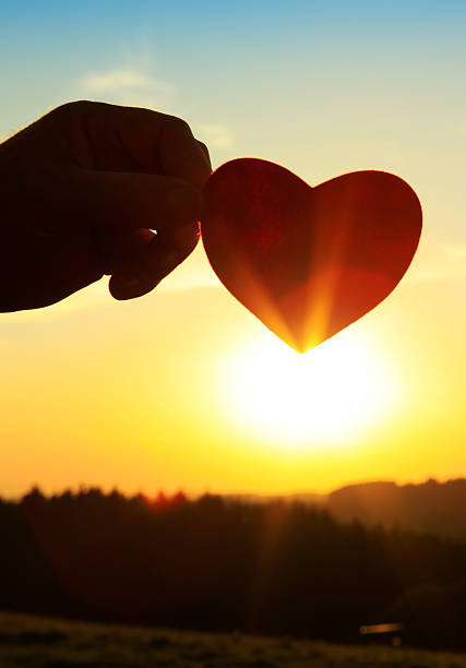 istock Hand with paper heart at sunrise. 614243034