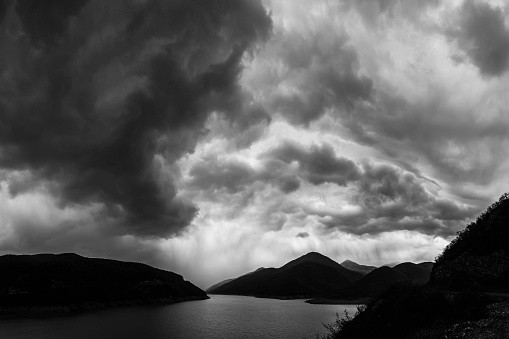 Dramatic sky and storm clouds above the Zhinvali water reservoir in Georgia. Reservoir is located among the mountains. Large panoramic image.
