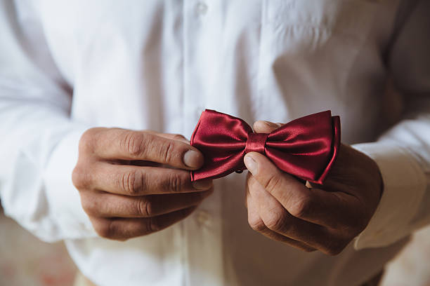 istock Wedding accessories. Groom holding red bow tie in his hand 614305610