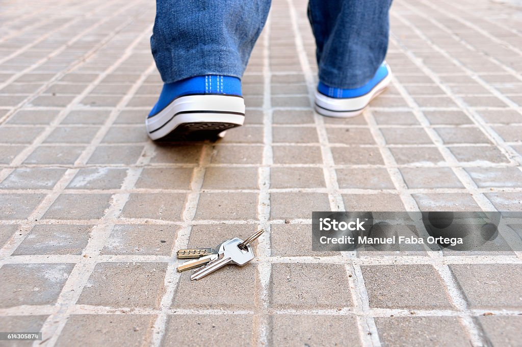 losing my keys Cropped rear view of a walking young who loses the home keys on the sidewalk street in the city Loss Stock Photo