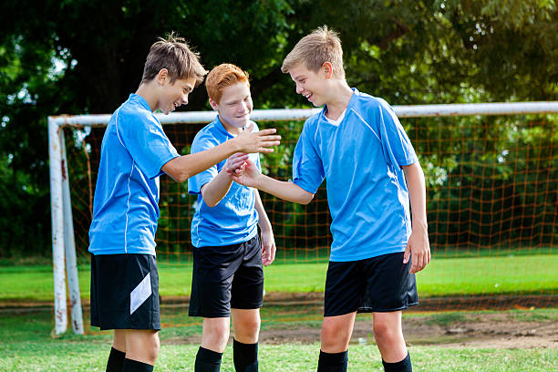 l’équipe de soccer des adolescents se félicite les uns les autres après avoir gagné le match - goalie soccer soccer player teenage boys photos et images de collection