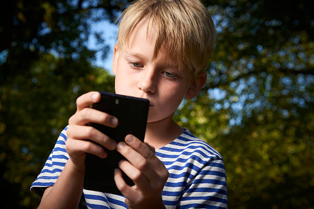 istock Child young boy with mobile phone outdoor 614309172