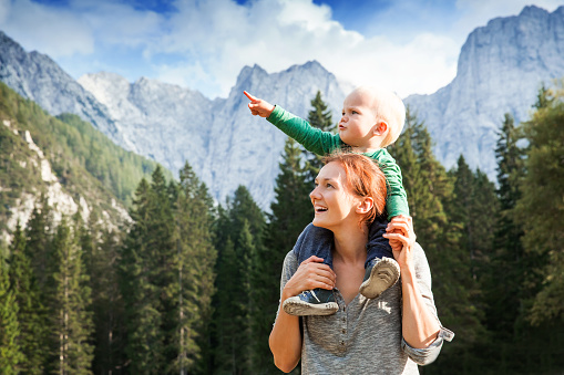 Happy mother and her child looking forward and pointing to sky. Family on trekking day in the mountains. Mangart, Julian Alps, National Park, Slovenia, Europe. Travel, Explore, Family, Future Concept
