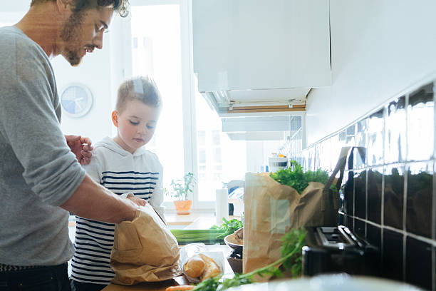 istock Father And Son Organizing Groceries In The Kitchen 614311928