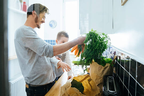 istock Father And Son Organizing Groceries In The Kitchen 614312188