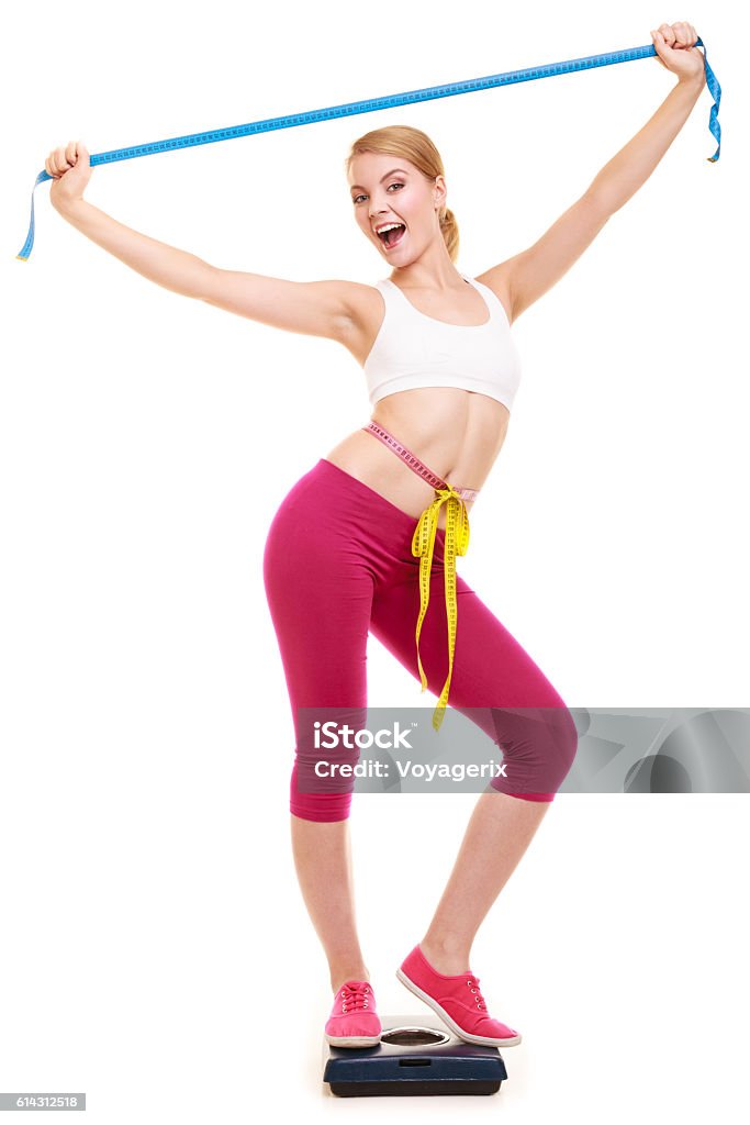 Woman measuring on weighing scale with raised arms Slimming and weight loss. Happy joyful young woman girl measuring with tape measures on weighing scale. Successful girl with raised arms hands. Healthy lifestyle concept. Isolated on white. Adult Stock Photo