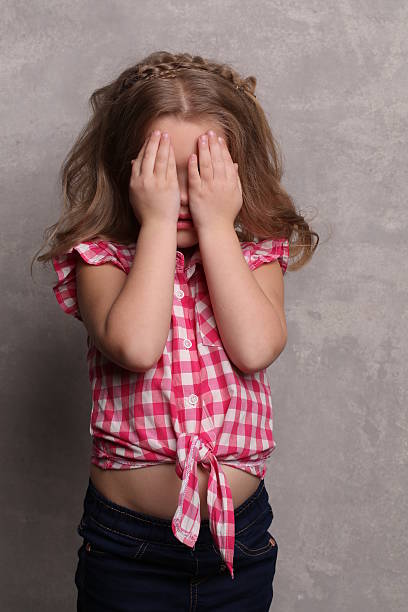 istock Kid covering her eyes with hands. Close up. Gray background 614313518