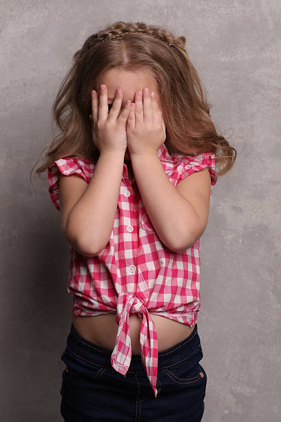 istock Baby covering her eyes with hands. Close up. Gray background 614313542