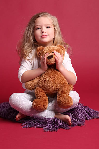 istock Baby in pajamas holding a bear. Red background 614315226
