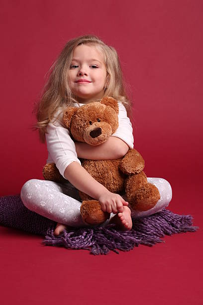 istock Lady in pajamas hugging a bear. Red background 614315262