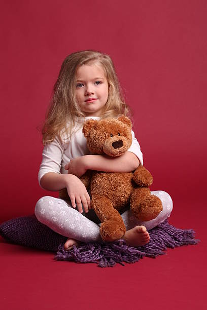 istock Child in pajamas hugging a bear. Red background 614315280
