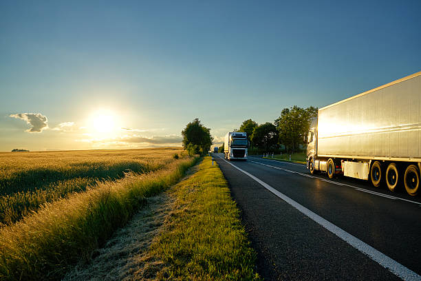 일몰에 도로에서 서로 에 대해 이동 트럭. - asphalt truck transportation mode of transport 뉴스 사진 이미지