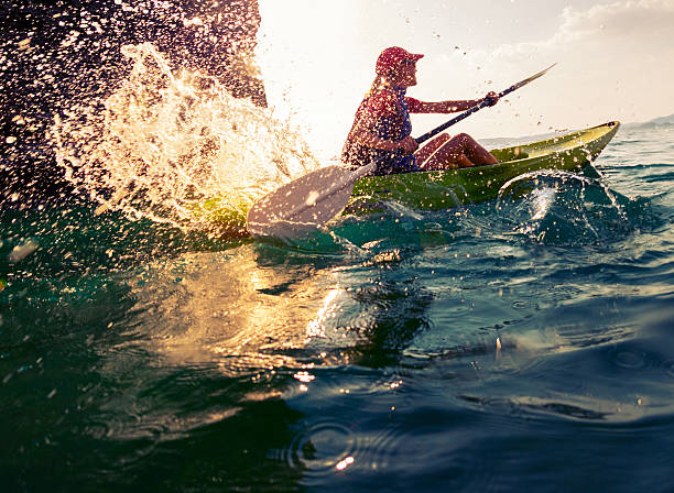 Woman with the kayak Young lady paddling hard the sea kayak with lots of splashes kayaking stock pictures, royalty-free photos & images