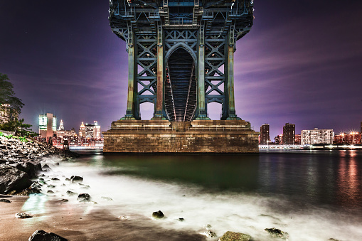 A long exposure of the Manhattan Bridge footing and the East River.