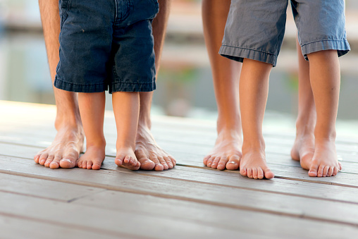 Young family standing on a dock showing their feet