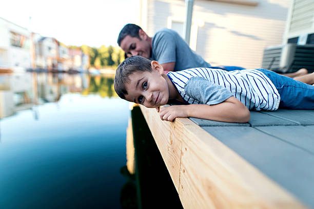istock Curious young boy laying on a dock looking at water 614321842