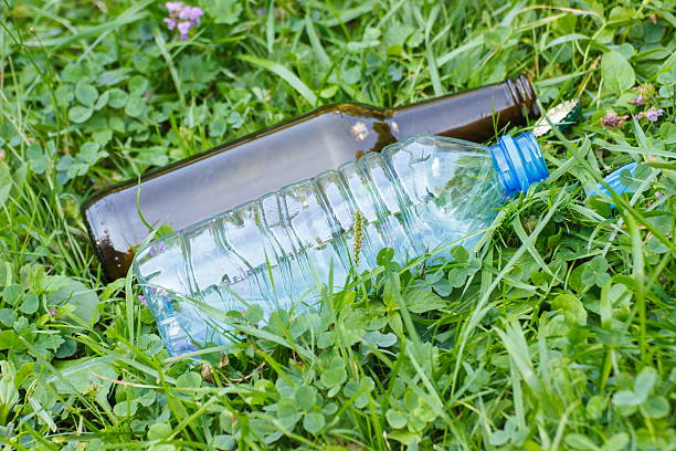 istock Plastic and glass bottle with bottle caps on grass 614323372