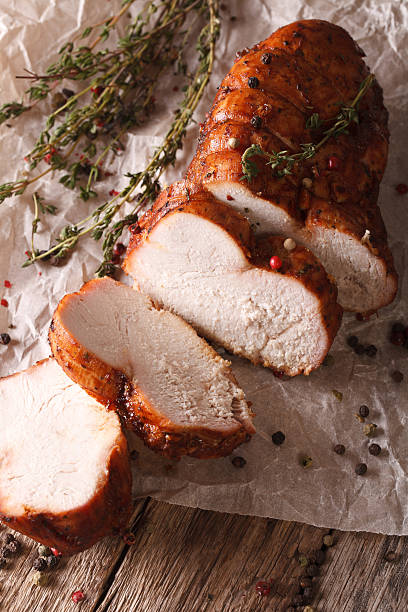 istock sliced roasted turkey fillet close up on paper. Vertical 614326860