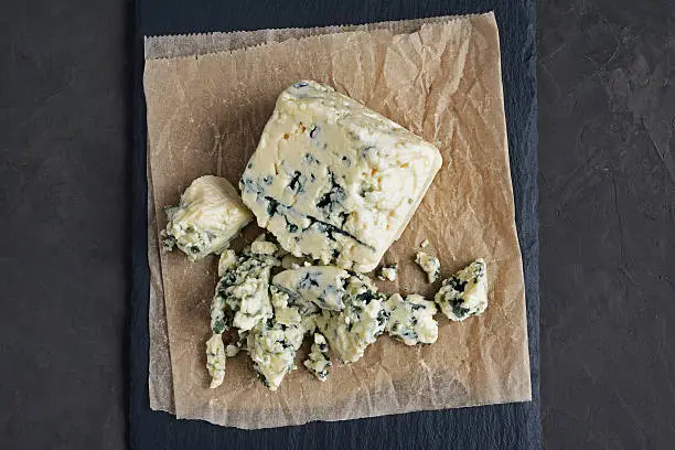 Delicious blue cheese on black slate background